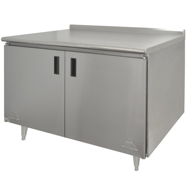 A stainless steel Advance Tabco work table with enclosed base and hinged doors.