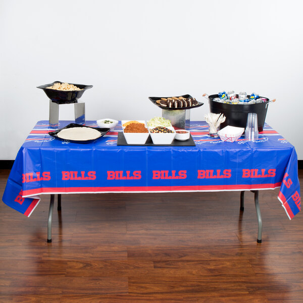 A Buffalo Bills plastic table cover on a table with food.