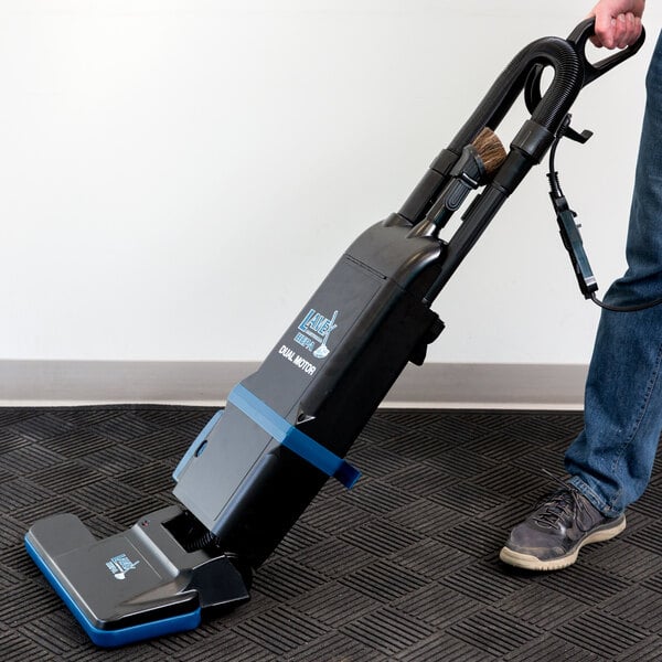 A person holding a Lavex dual motor upright bagged vacuum cleaner.