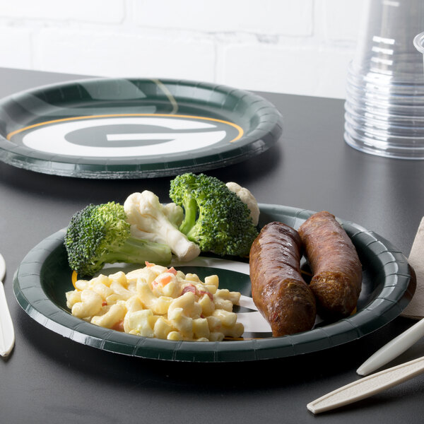A table set with Creative Converting Green Bay Packers paper dinner plates filled with food.