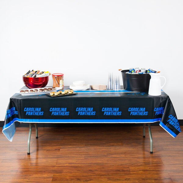 A table with a black tablecloth with blue writing and food on it.