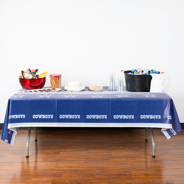 A table with a Dallas Cowboys plastic table cover in blue.