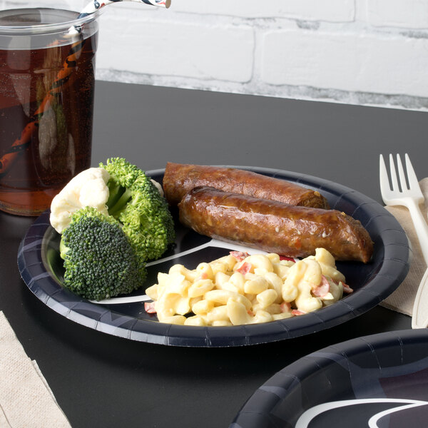 A Creative Converting Houston Texans paper dinner plate with sausage and broccoli on it on a table with a glass of beer.