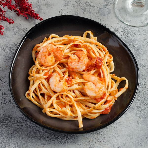 A plate of pasta with shrimp and tomato sauce in a black Reserve by Libbey Pebblebrook bowl.