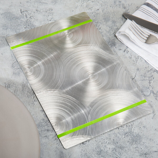 A Menu Solutions Alumitique aluminum menu board with a green band on a table with a silver plate and fork.