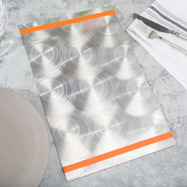 A silver Menu Solutions Alumitique menu board with orange bands on a table with silverware and a white napkin.