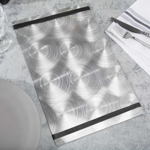 A silver Menu Solutions Alumitique menu board with black bands on a table with silverware and a white plate.