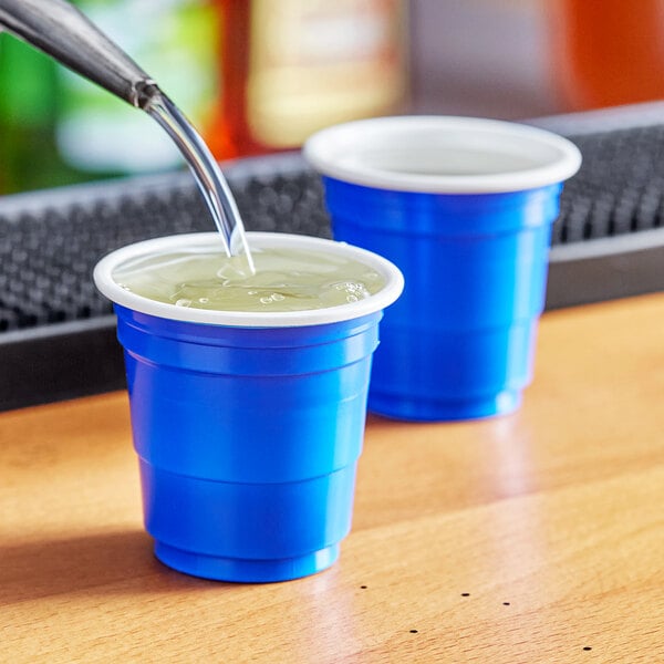 A close up of liquid being poured into a Choice blue plastic cup.