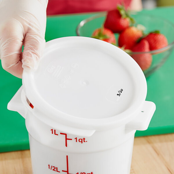 A gloved hand holds a Choice white polypropylene food storage container lid.