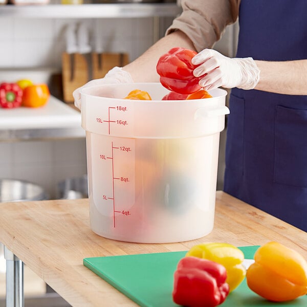 A person in gloves putting red and yellow bell peppers into a Choice translucent food storage container.