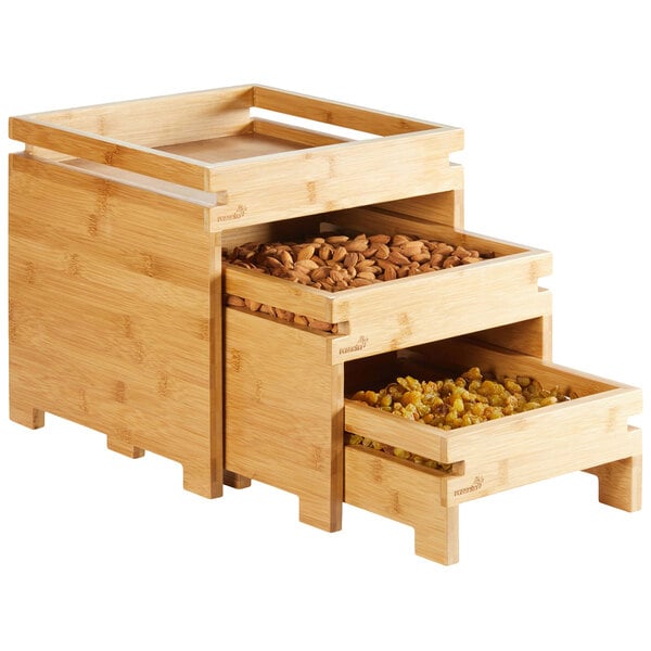 A Rosseto Natura bamboo 3-tier fruit stand with wooden drawers holding nuts and dried fruits.