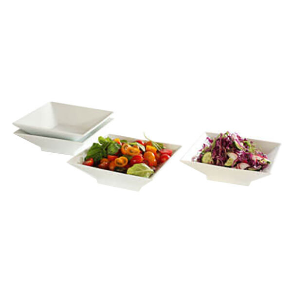 Three white Rosseto porcelain square bowls filled with salad and vegetables.