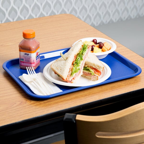 A sandwich and fruit on a blue plastic fast food tray with a plastic fork and spoon.