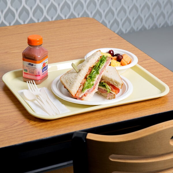 A sandwich and fruit on a beige plastic fast food tray.