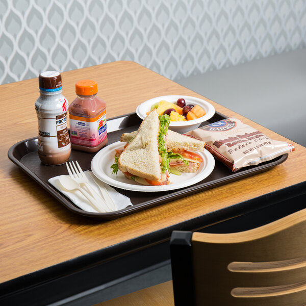 A Choice chocolate brown plastic fast food tray with a sandwich, a bowl of fruit, and a drink on it.