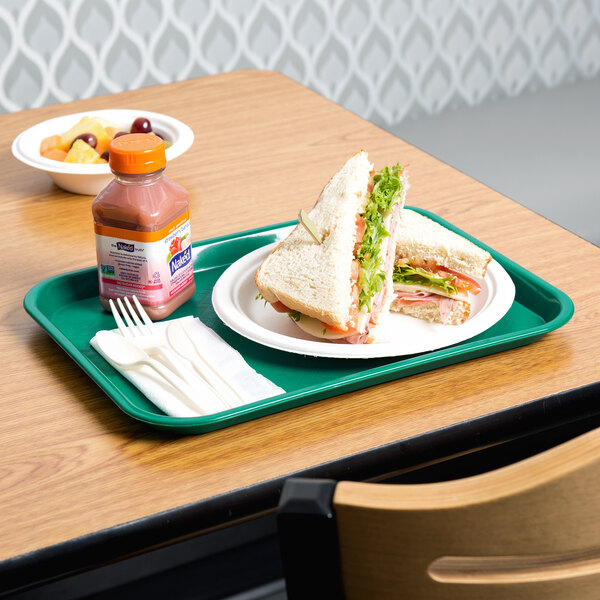 A teal plastic fast food tray with a sandwich and a bottle of juice on it.