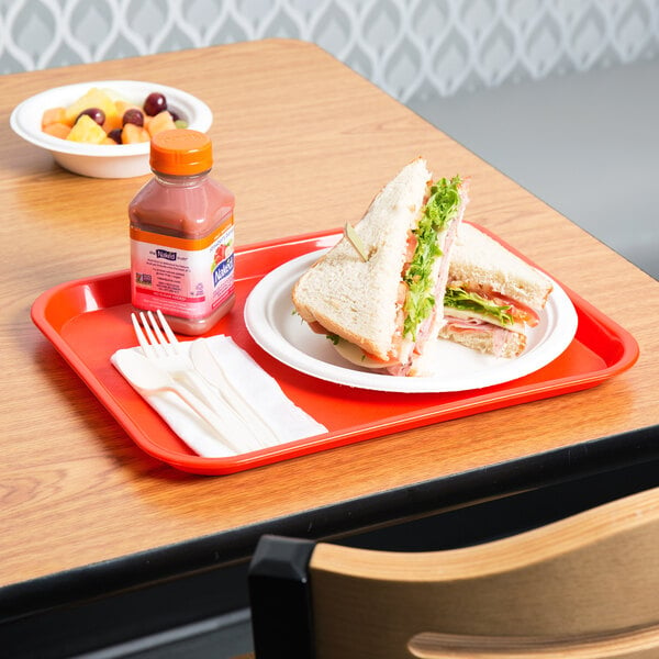 An orange plastic fast food tray with a sandwich and a bottle of juice on it.