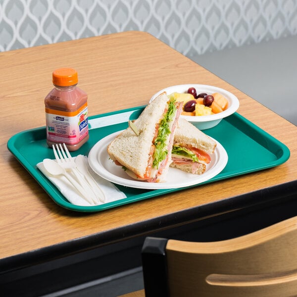 A teal plastic fast food tray with a sandwich and fruit on it.