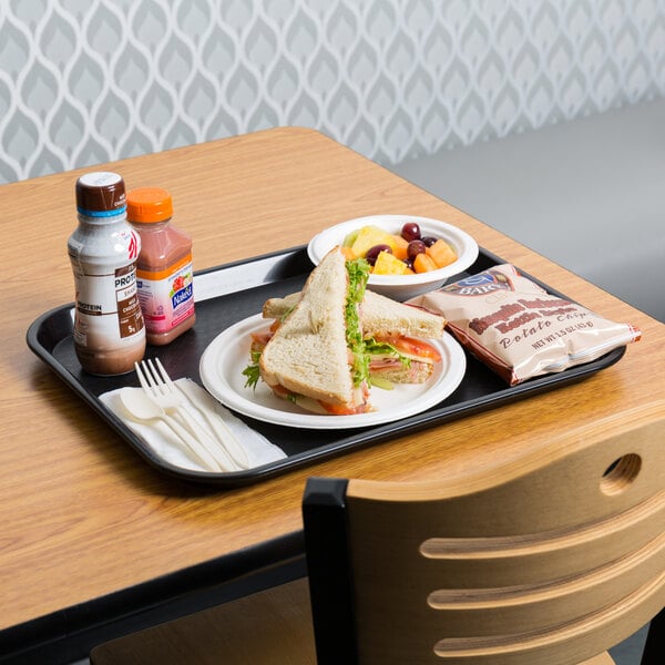 A black plastic fast food tray with a sandwich and drinks on it.