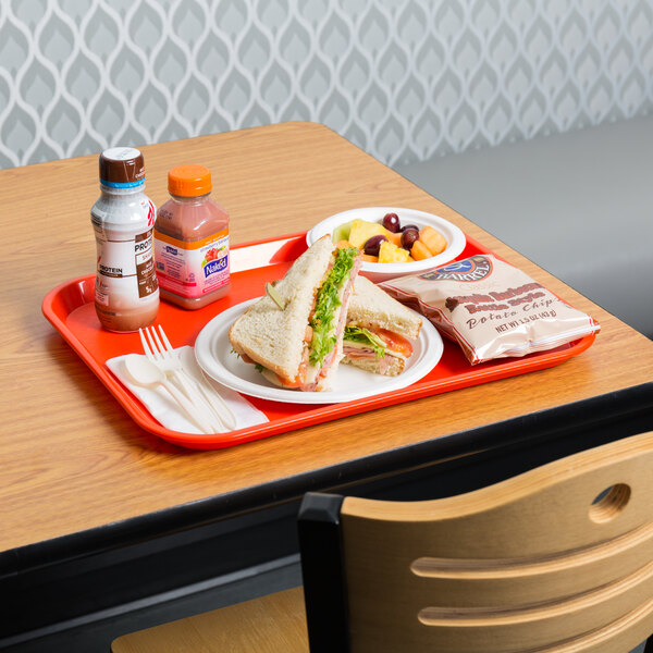 An orange plastic fast food tray with a sandwich, fruit, and a drink on it.