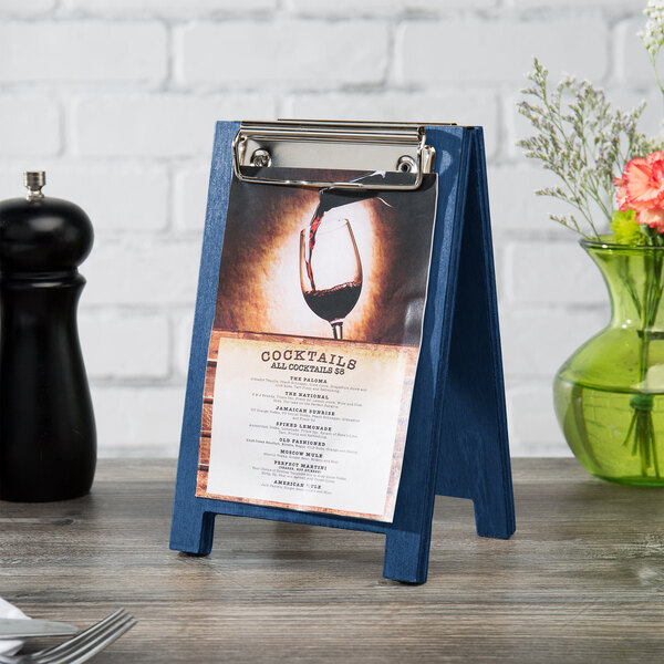 A Menu Solutions True Blue Wood Sandwich Menu Board Tent with Clip on a table.