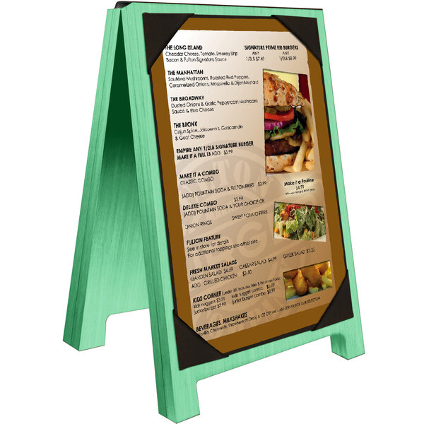 A Menu Solutions washed teal wood sandwich menu board with picture corners on a white table with a menu on it.