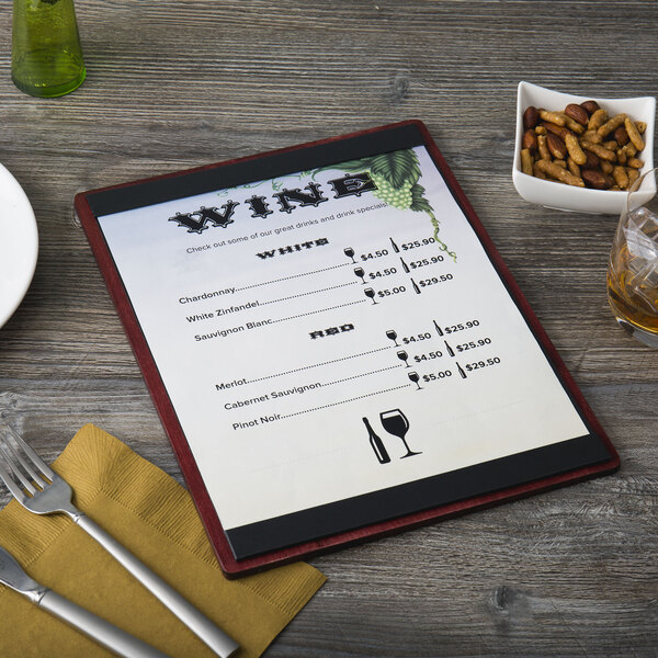A customizable mahogany wood menu board on a table with a menu, fork, and knife.