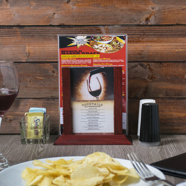 A mahogany wood menu holder with a menu on a table with a plate of potato chips.