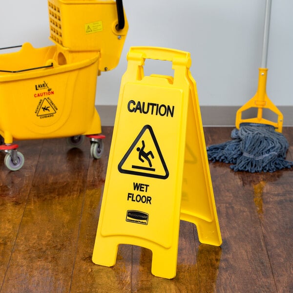 A yellow Rubbermaid "Caution Wet Floor" sign next to mop and buckets.