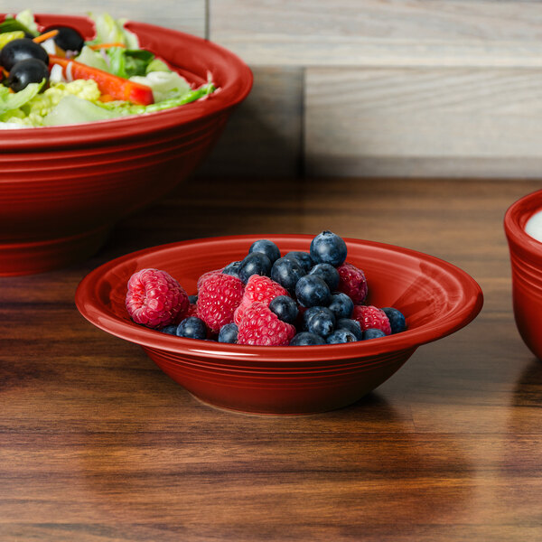 A bowl of salad with blueberries and raspberries in a red Fiesta cereal bowl.