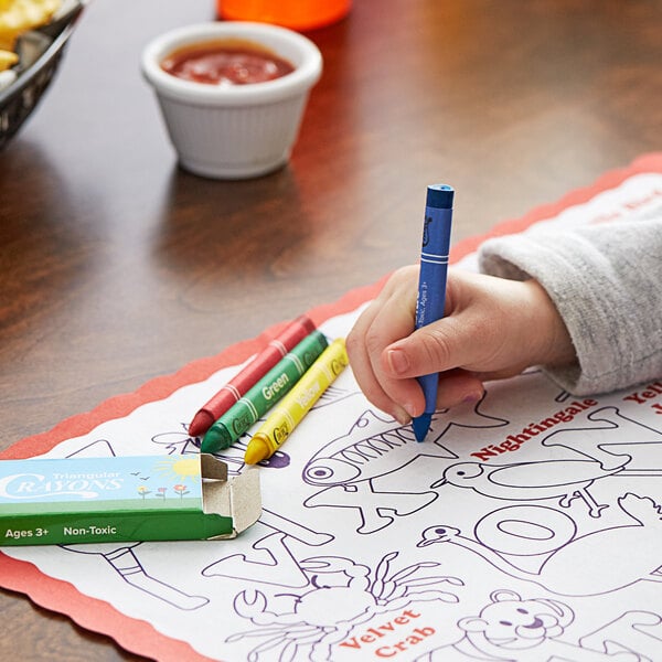 A child coloring on a paper with a blue Choice triangular crayon in a green print box.