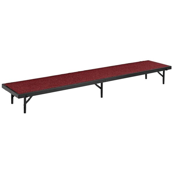 A long rectangular National Public Seating stage riser with red carpet.