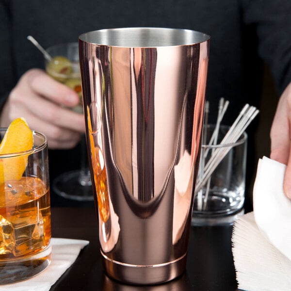 A man using a Barfly copper cocktail shaker tin to make a drink.