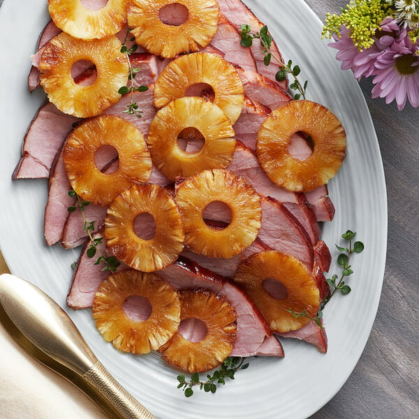 A plate of ham and Regal pineapple rings on a table at a catering event.