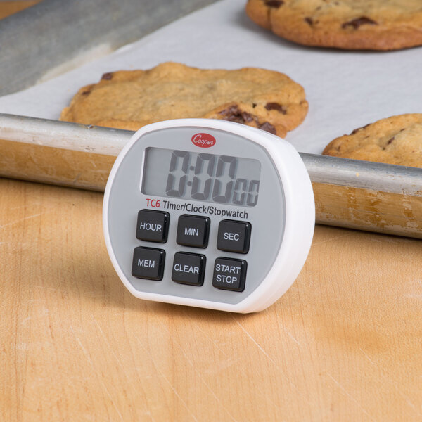 A Cooper-Atkins digital timer on a baking sheet with cookies.