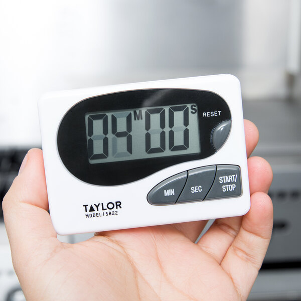 A hand holding a Taylor digital kitchen timer.