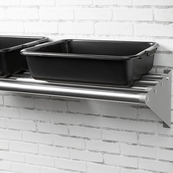 Two black containers on a Regency stainless steel wall mounted shelf.