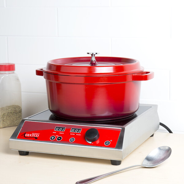 A red GET Heiss cast aluminum dutch oven with a lid on a counter.