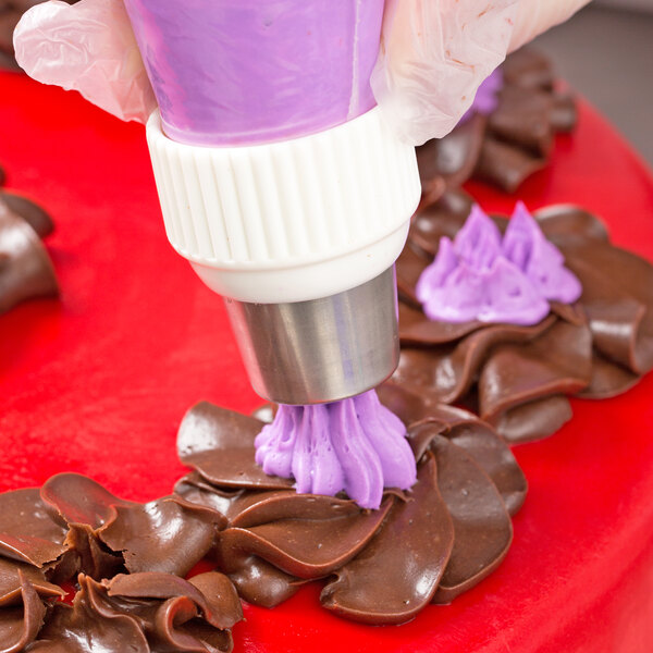 A person using an Ateco Russian piping tip and a pastry bag with purple icing to decorate a cake.