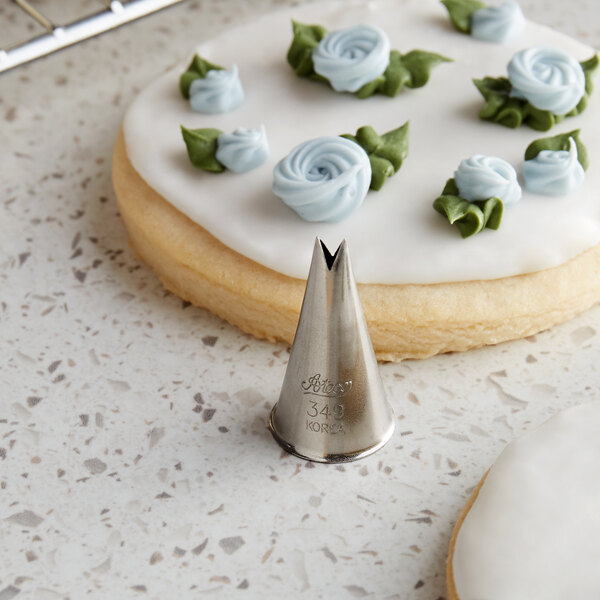 A cookie with frosting flowers piped on top using an Ateco leaf piping tip.