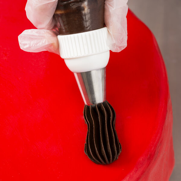 A hand using an Ateco closed star piping tip on a pastry bag to frost a cake.