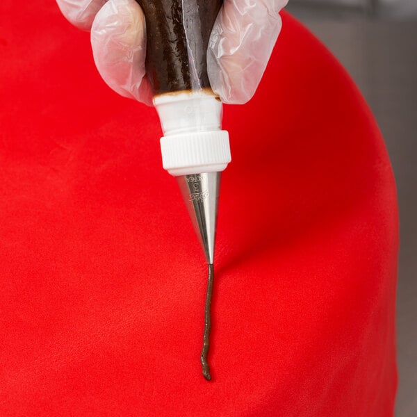 A person holding a pastry bag with Ateco 3 Plain Piping Tip on a red cake.