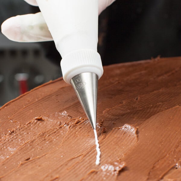 A person using an Ateco pastry bag with a white tip to frost a cake.