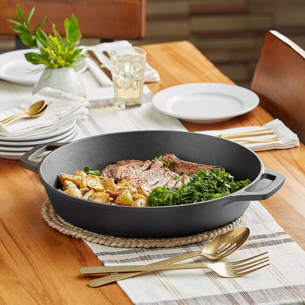 A Valor pre-seasoned cast iron skillet filled with meat and vegetables on a table.