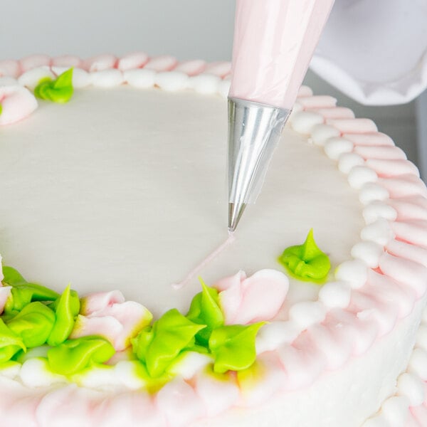 A person using an Ateco plain piping tip with a pastry bag to decorate a cake.