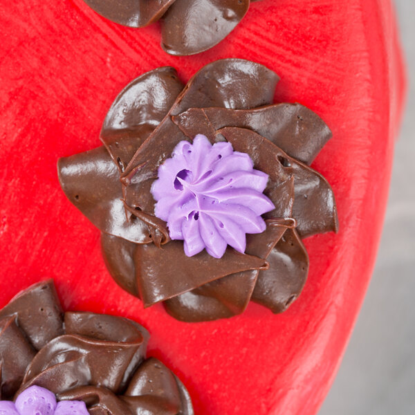 Chocolate frosting flowers made with an Ateco Russian piping tip on a red surface.