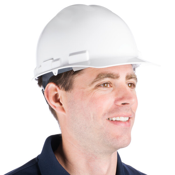 A man wearing a Cordova white cap style hard hat with a 6-point ratchet suspension smiles at the camera.