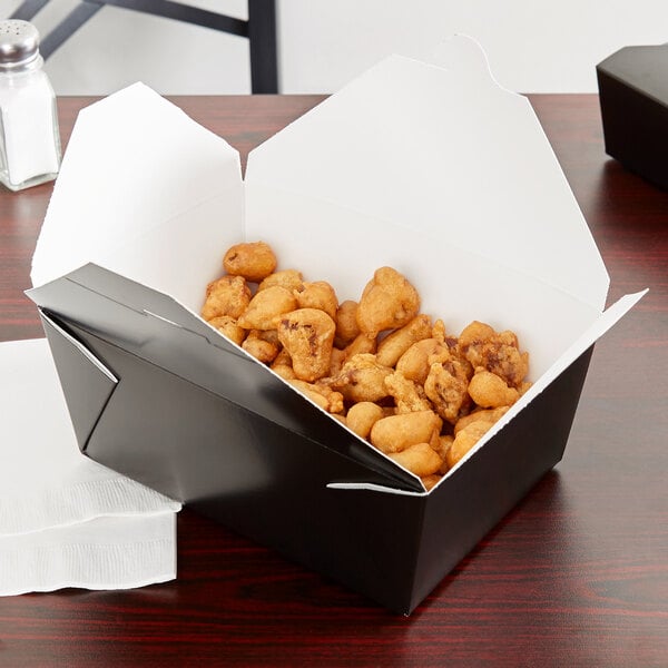 A black Fold-Pak Bio-Pak take-out box filled with fried food on a table.