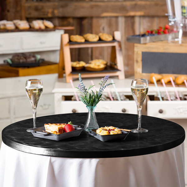 A black aluminum table cover with a random swirl pattern on a table with food and drinks.