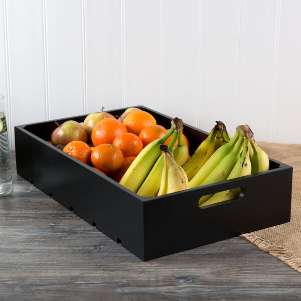 A Tablecraft black wood crate filled with bananas and oranges on a table.